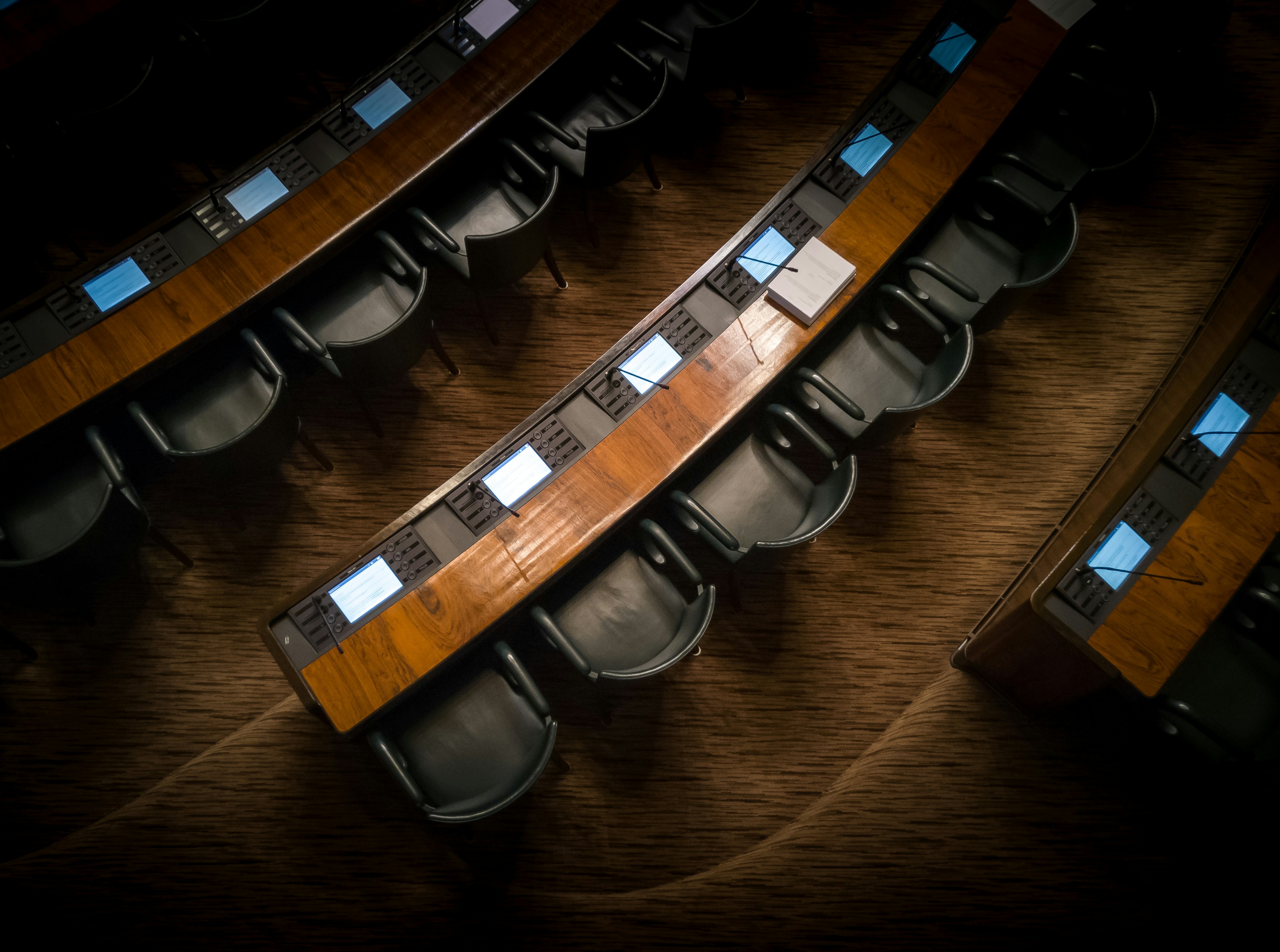 Rows of empty seats in a legislative chamber, waiting to be filled.